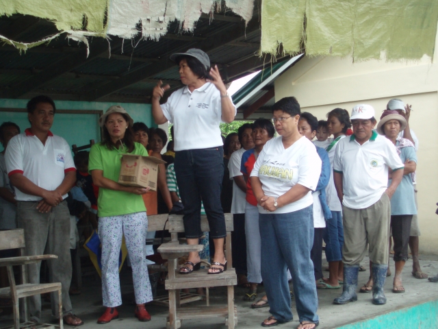 Mrs. Linda Macalintal, OMASC Philippine Liaison, introducing OMASC at Brgy. Santiago distribution. Far left is Brgy Captain Marciano Bacay.  Mrs Edna Llamoso, MSW, is the lady in white shirt, forefront.
